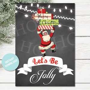 May include: A black chalkboard with white string lights and a cartoon Santa Claus holding a stack of presents that say "Merry Christmas". The text "Let's Be Jolly" is written in white on a white banner.