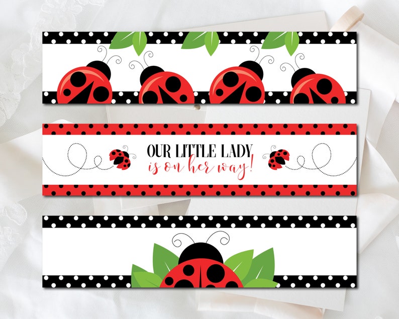 May include: Three rectangular banners with ladybug designs. The top and bottom banners feature red ladybugs with black spots and antennae, set against a white background with black polka dots. The middle banner reads "OUR LITTLE LADY is on her way!" in red.