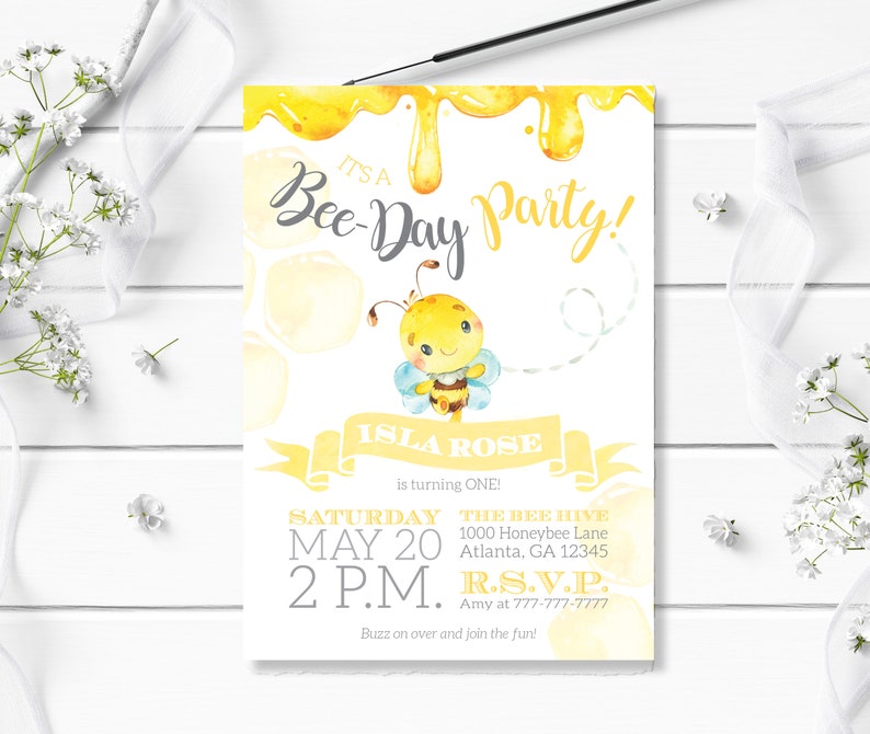 May include: A yellow and white bee-themed birthday party invitation with a cartoon bee illustration. The invitation reads "It's a Bee-Day Party!" and includes the name "Isla Rose" and the text "is turning ONE!"  The invitation also includes the date, time, and location of the party.