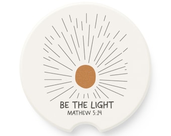 Peut inclure: Sous-verre en céramique blanche avec un motif de soleil rayonnant et le texte "BE THE LIGHT" et "MATTHEW 5:14".
