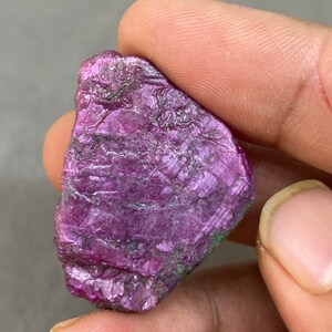 Könnte beinhalten: Ein roher, violetter, roher Rubin-Edelstein mit einer natürlichen, unregelmäßigen Form.