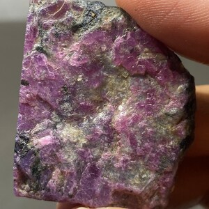 Op de afbeelding: Een ruwe, roze en grijze edelsteen met een natuurlijke, onbewerkte afwerking. De edelsteen heeft een ruwe, onregelmatige vorm en is een natuurlijk, ruw exemplaar.