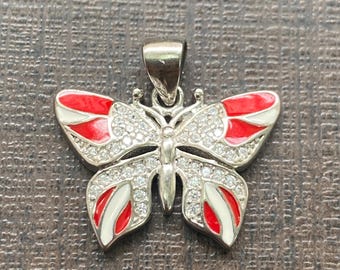May include: A silver butterfly pendant with red and white enamel and clear rhinestones.