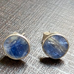 May include: A pair of silver stud earrings with blue and clear gemstone accents.