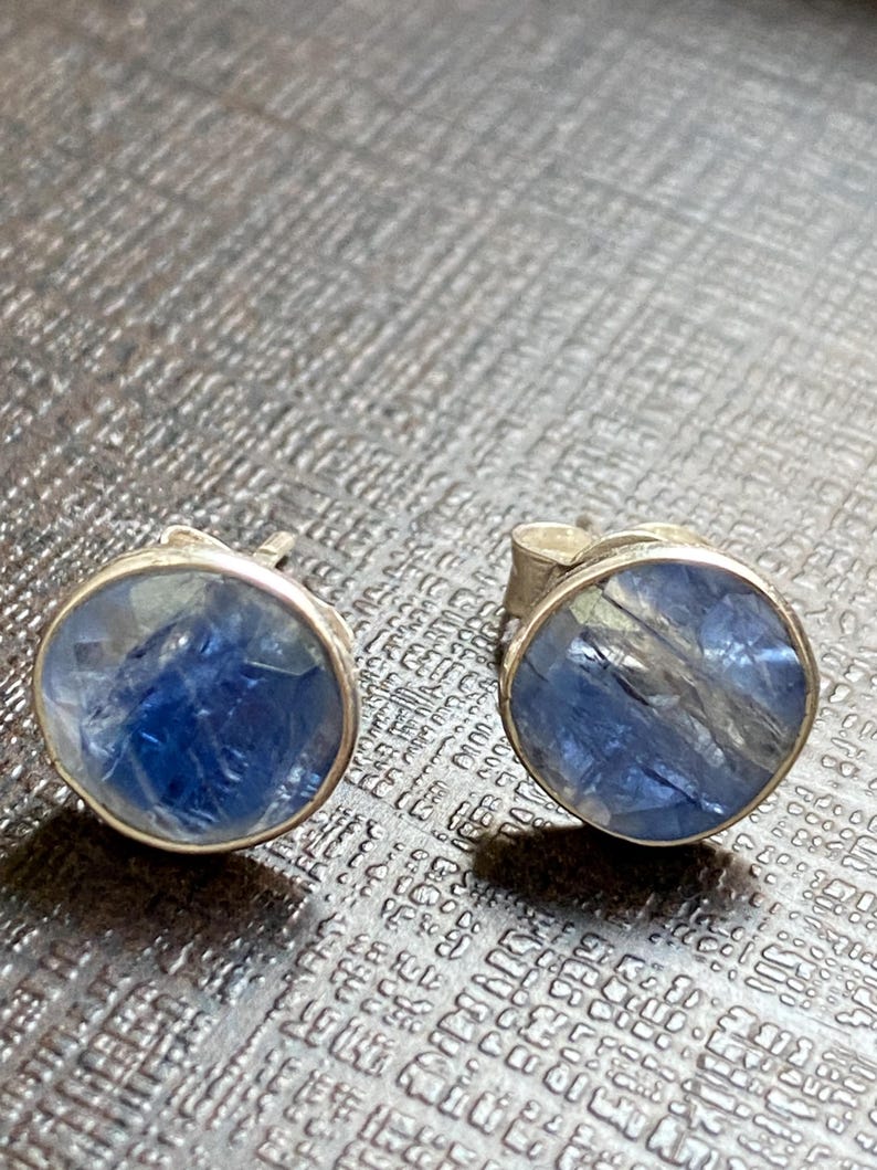 May include: A pair of silver stud earrings with blue and clear gemstone accents.
