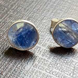 May include: A pair of silver earrings with round blue gemstone settings.