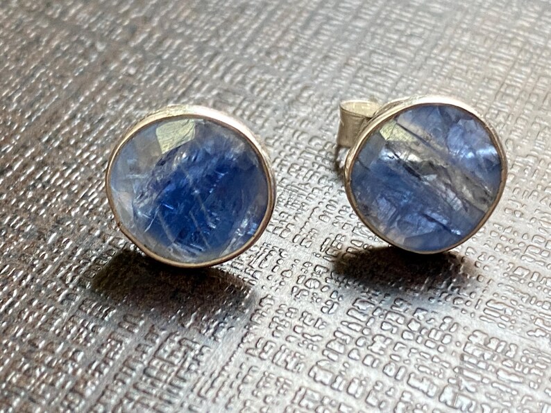 May include: A pair of silver earrings with round blue gemstone settings.