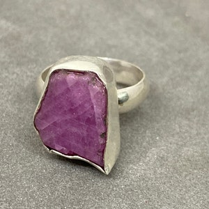Puede incluir: Un anillo de plata con una gran piedra preciosa púrpura en bruto engastada en el centro.