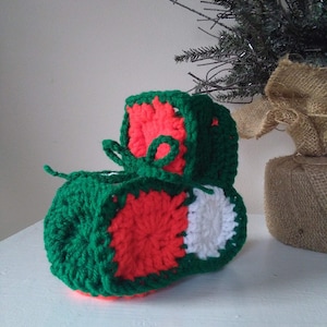 May include: A crocheted Christmas stocking in green, red, and white. The stocking is shaped like a boot and has a white pom-pom on top.