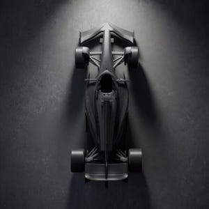 Puede incluir: Vista cenital de un coche de carreras de Fórmula 1 negro. El vehículo está centrado e iluminado por un foco, mostrando su diseño aerodinámico. Los neumáticos, el alerón y la cabina son visibles sobre un fondo oscuro.