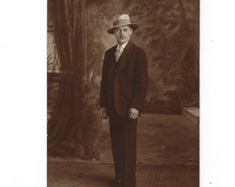 The hat! Undated portrait of a fashionable man in a pin-striped suit posed against a painted backdrop.