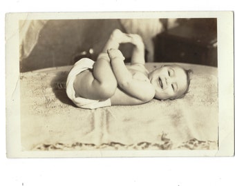 Happy baby! Undated original RPPC photo of a child posed on a cushion or bed.