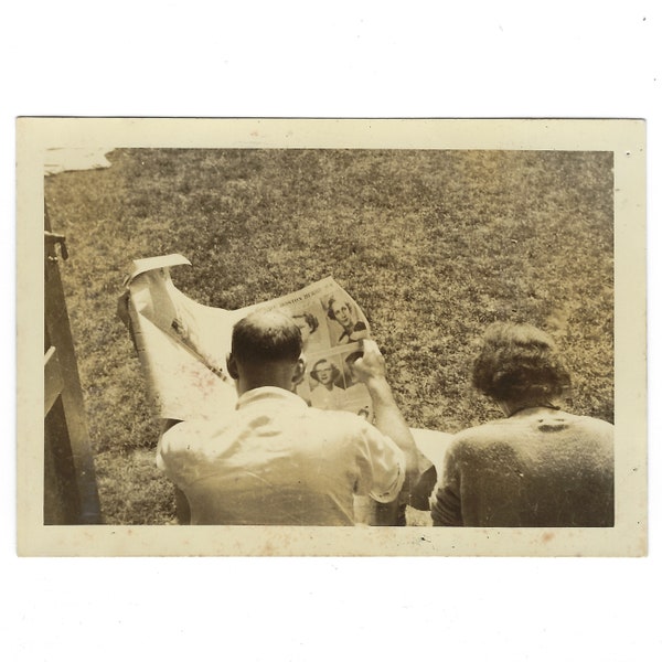 Reading the newspaper on the porch. Vintage snapshot photo.