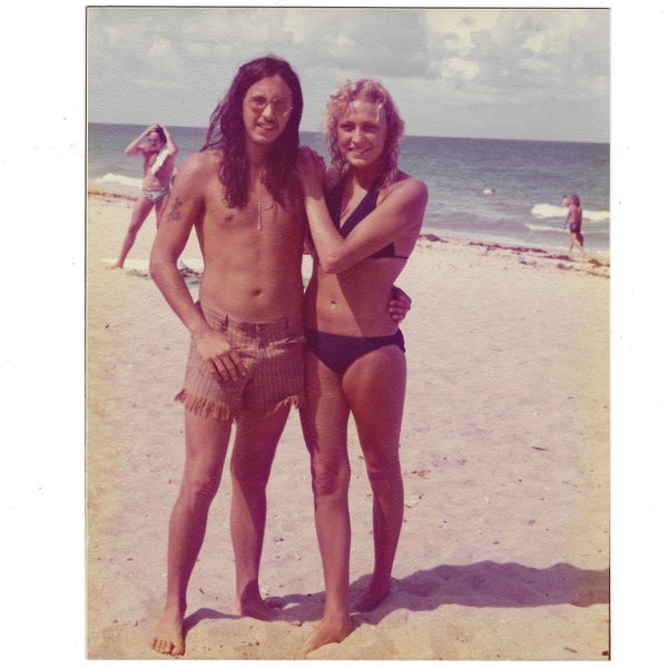 70s beach couple. Vintage snapshot photo of a young man and woman ready for a swim.