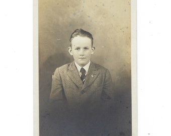 Serious little dude. Undated RPPC portrait of a boy in a suit and tie with a U.S. flag pin on his lapel.