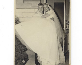 Over the threshold. Undated photo of a handsome groom carrying his pretty blonde bride.