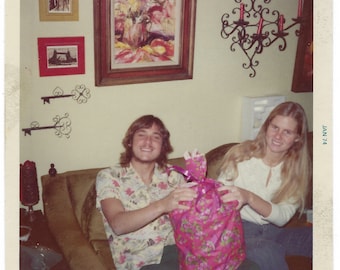 Big Pink Package! 1970s vintage snapshot of a young woman presenting a young man with a gift.