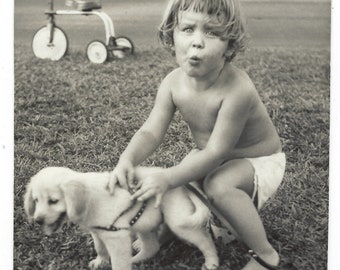 Uh-oh! Undated original photo of a toddler and puppy with a tricycle in the background.