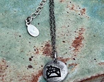 May include: A silver chain necklace with a small round pendant featuring a black and white image of an envelope with a heart inside.