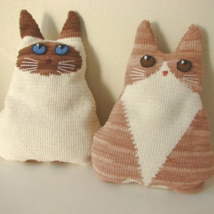 May include: Two crocheted cat plushies, one white with blue eyes and one brown and white with brown eyes.