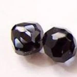 Peut inclure: Deux perles de verre facettées gris foncé. Les perles sont rondes et ont une finition brillante.