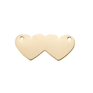 May include: A gold-toned metal jewelry connector featuring two conjoined heart shapes. The piece has a smooth, polished surface and includes a small circular hole on the outer edge of each heart for attachment purposes in jewelry making projects.