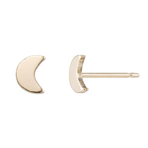 May include: A pair of gold crescent moon stud earrings.