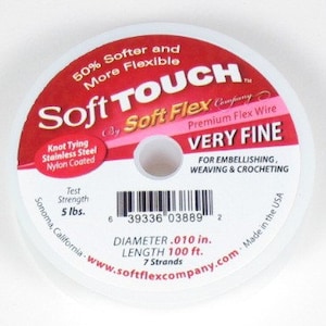 May include: A spool of Soft Touch Very Fine premium flex wire for embellishing, weaving, and crocheting. The label is white and red, with text indicating a diameter of .010 inches and a length of 100 feet. The wire is nylon coated and has a test strength of 5 lbs.