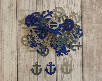 May include: A pile of blue and gray paper anchor shapes on a light wood background. There are three larger anchors at the bottom of the image.