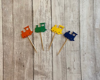 Puede incluir: Cuatro pinchos de madera con recortes de tren de papel de colores. Los trenes son naranja, verde, amarillo y azul.