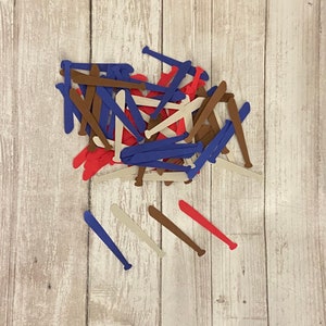 May include: A pile of paper baseball bats in red, blue, brown, and white. The bats are scattered on a light wood surface.