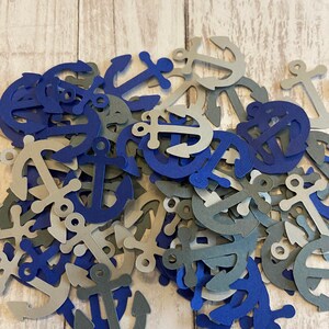 Puede incluir: Un mont&oacute;n de confeti de papel en forma de ancla de color azul y gris. Las ancras son de varios tama&ntilde;os y formas.