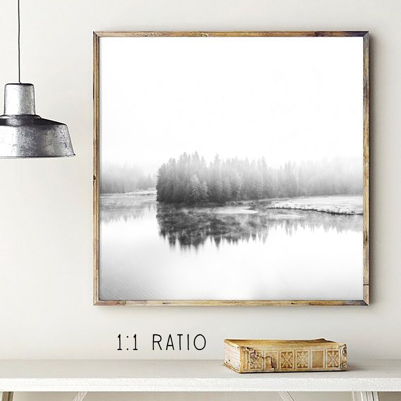 May include: Black and white framed print of a misty lake scene with a forested island. The artwork is in a wooden frame and hangs on a white wall. The text "1:1 RATIO" is below the frame.