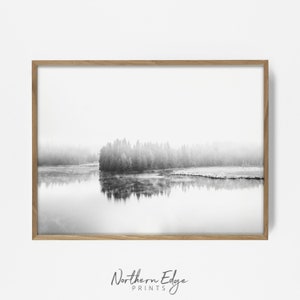 May include: Black and white landscape print featuring a tranquil lake reflecting a forested shoreline. The image is framed in a light brown wooden frame. The text "Northern Edge Prints" is at the bottom.