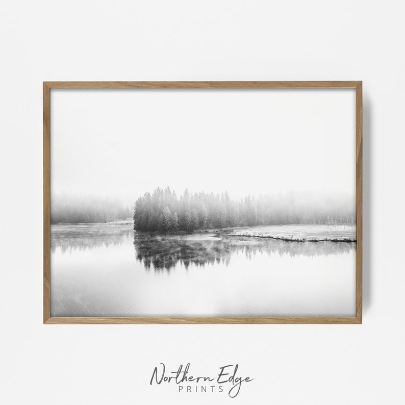 May include: Black and white landscape print featuring a tranquil lake reflecting a forested shoreline. The image is framed in a light brown wooden frame. The text "Northern Edge Prints" is at the bottom.