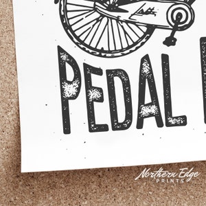 K&ouml;nnte beinhalten: Schwarzwei&szlig;-Illustration eines Fahrradrads mit dem darunter gedruckten Text "PEDAL HARDER".
