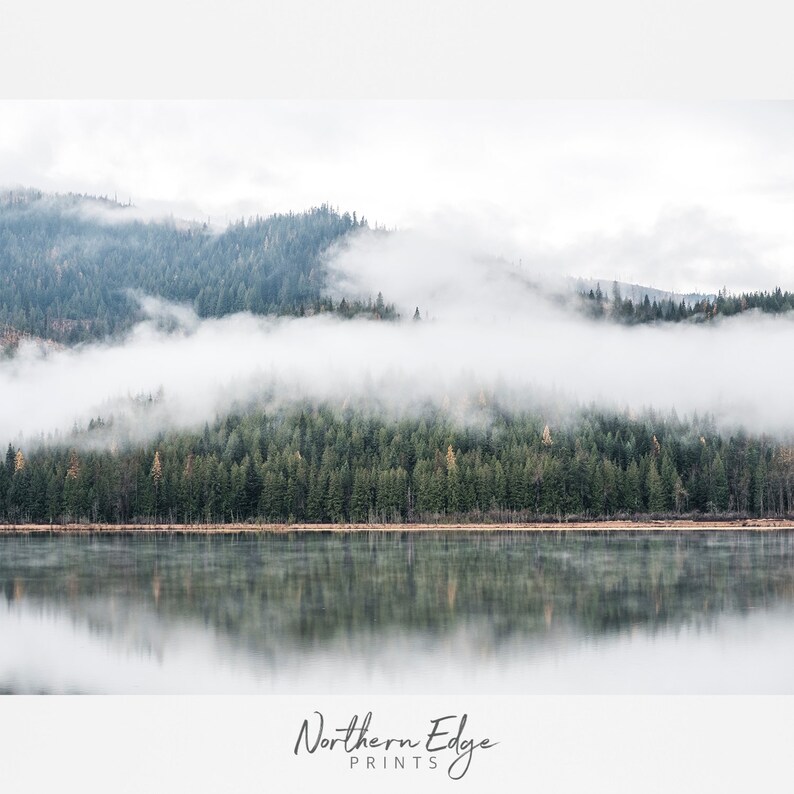 May include: A serene landscape photograph featuring a tranquil lake reflecting a forested hillside shrouded in mist. The image showcases a palette of greens, grays, and whites, with the text "Northern Edge Prints" at the bottom.