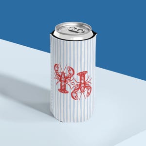 May include: A white and blue striped can cooler featuring two red lobster illustrations. The cooler is designed to hold a standard-sized beverage can. The background is a gradient of blue and white.