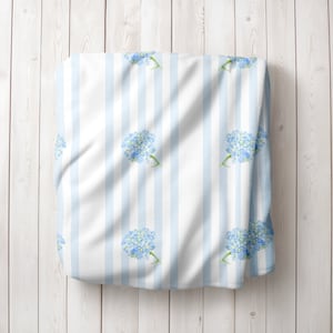 May include: White fabric with blue stripes and a repeating pattern of light blue watercolour hydrangea flowers.