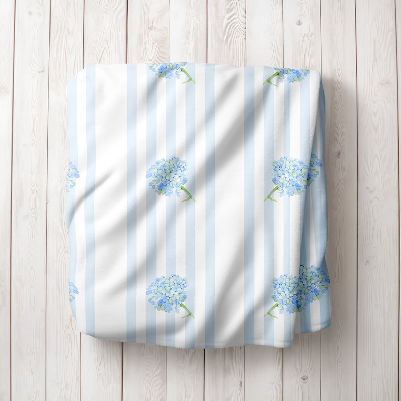 May include: White fabric with blue stripes and a repeating pattern of light blue watercolour hydrangea flowers.