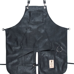 May include: Black leather apron with multiple pockets and a logo that says "The Barber" with a crossed razor and top hat design.