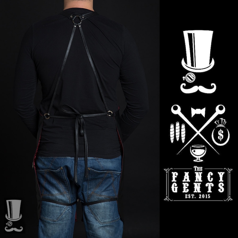 May include: A black leather apron with adjustable straps and a red lining. The apron is worn by a person with a black shirt and blue jeans. The image also includes a logo with the text "The Fancy Gents Est. 2015" and a stylized illustration of a gentleman with a top hat, monocle, mustache, bow tie, and crossed cigars.