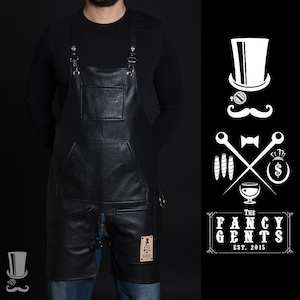 May include: Black leather apron with adjustable straps, two large pockets, and a smaller pocket on the front. The apron has a small patch with a logo that says "The Fancy Gents Est. 2015".