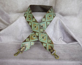 May include: A brown leather strap with a turquoise and gold geometric pattern. The strap has two metal clasps.