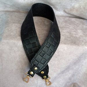 May include: Black leather woven strap with gold metal hardware and two clasps.