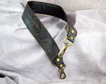 May include: A dark brown leather bag strap featuring an embossed floral pattern throughout the surface. The strap includes two brass-toned metal swivel lobster clasps attached with matching brass rivets at both ends for secure fastening.