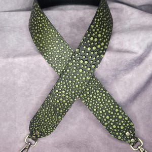 May include: A green and black leather strap with a dotted pattern and gold metal clasps. The strap is designed to be used as a replacement strap for a bag.