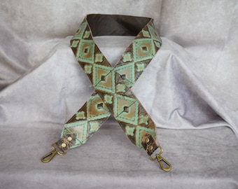 May include: A brown leather strap with a turquoise and gold geometric pattern. The strap has two metal clasps.