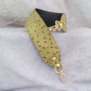May include: A green ostrich leather shoulder strap with gold hardware and a swivel hook.
