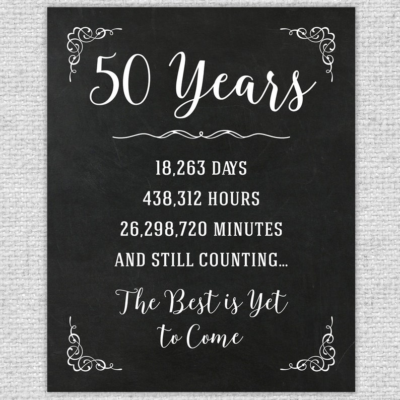 May include: Black and white chalkboard sign with the text "50 Years" and the number of days, hours, and minutes in 50 years. The sign also includes the text "The Best is Yet to Come".